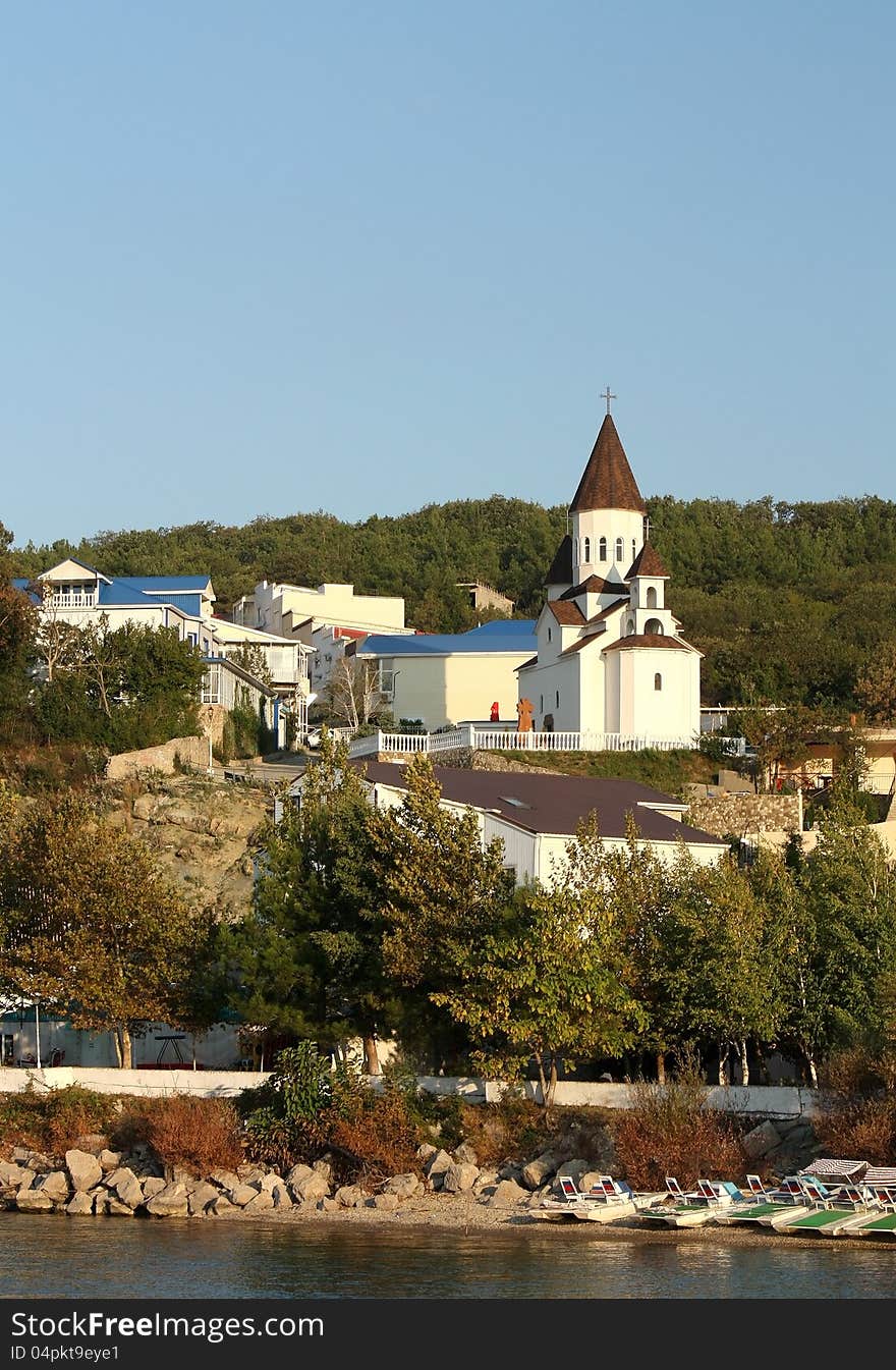 Church among  green trees on the river's bank. Church among  green trees on the river's bank