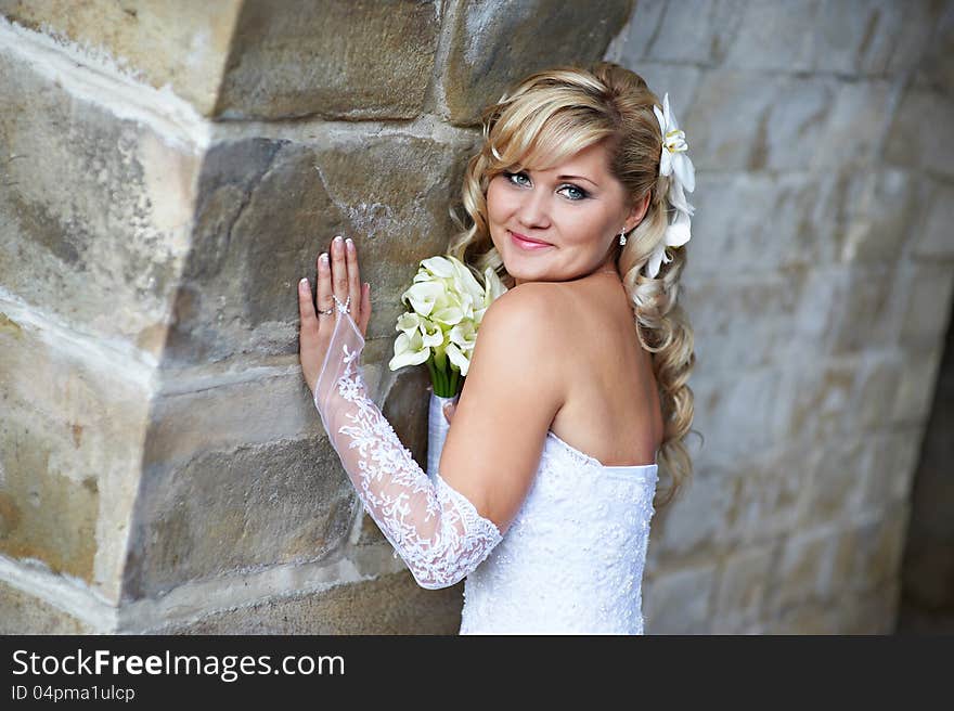 Happy bride near stone wall on wedding walk