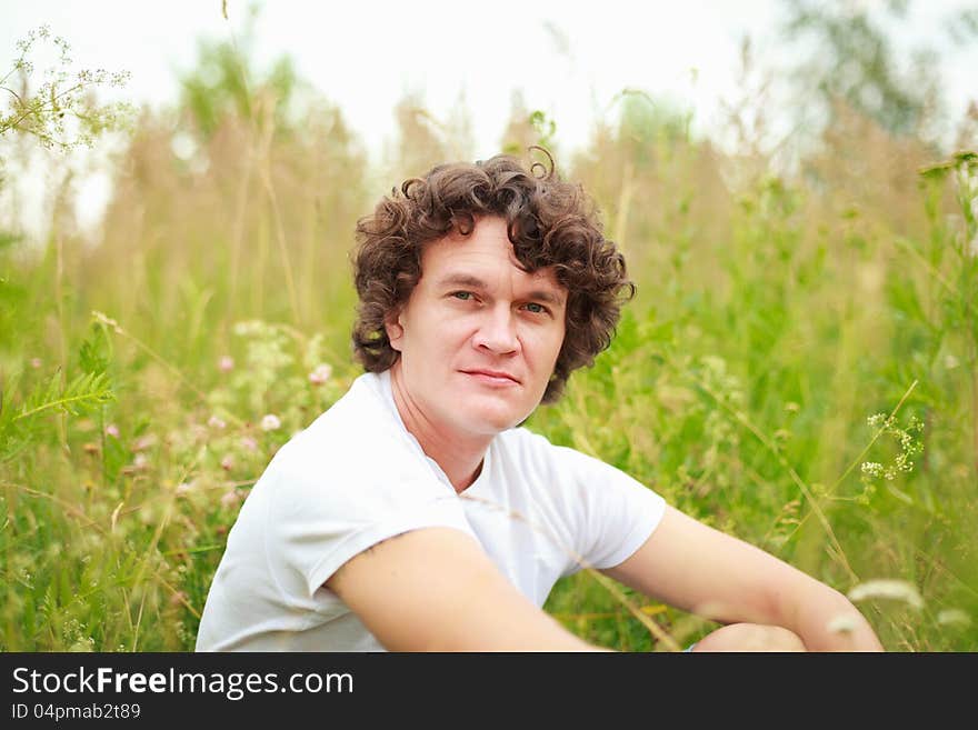 A young man sitting among flowering meadows. A young man sitting among flowering meadows.