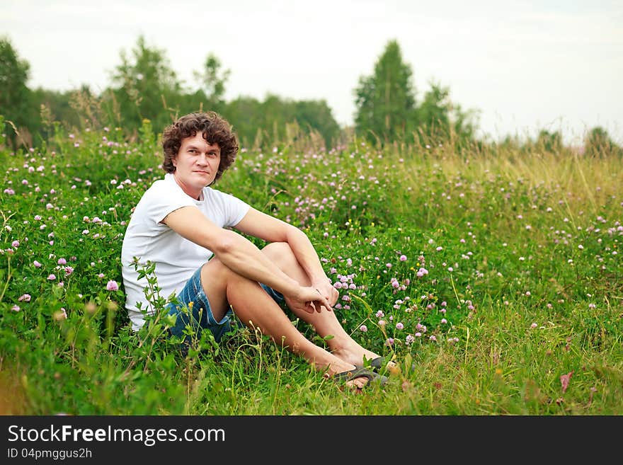 A young man sitting among flowering meadows. A young man sitting among flowering meadows.