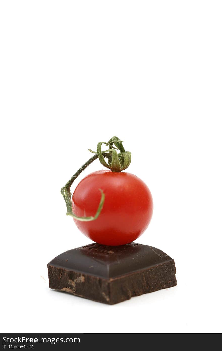 Fresh tomatoe on piece of dark chocolate presented on white. Fresh tomatoe on piece of dark chocolate presented on white