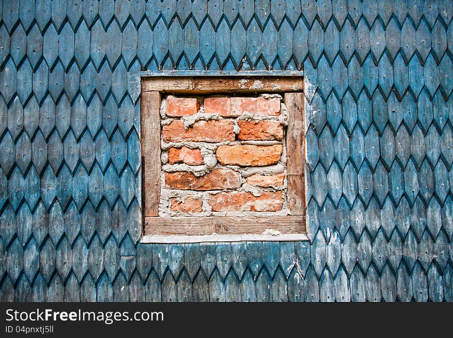 Wooden wall of the old house and window with bricks