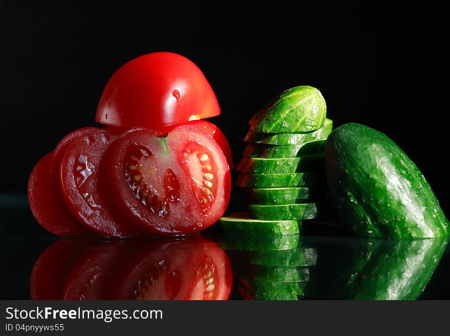 Sliced tomatoes and cucumber on black background. Sliced tomatoes and cucumber on black background