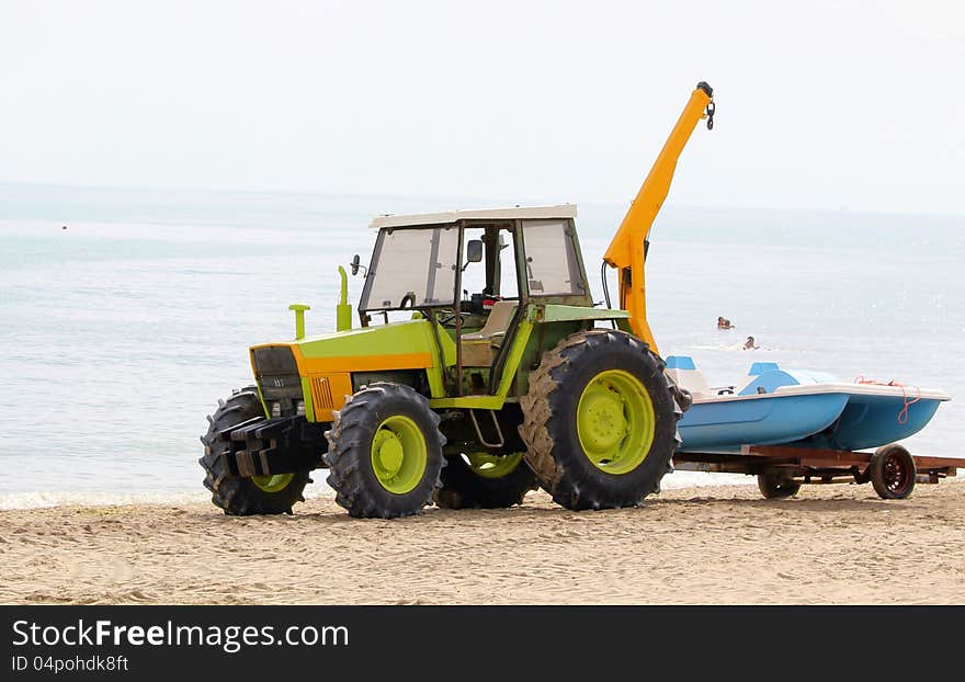 Tractor raises rowing boat - location near the sea on the beach. Tractor raises rowing boat - location near the sea on the beach.