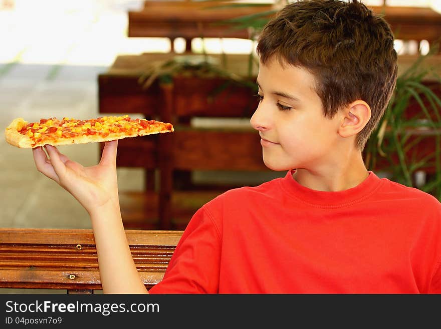 A boy and a slice of pizza outdoor. A boy and a slice of pizza outdoor