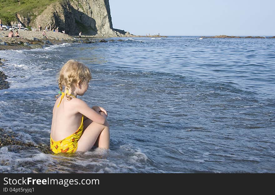 Little girl sitting on the bank of Japan Sea