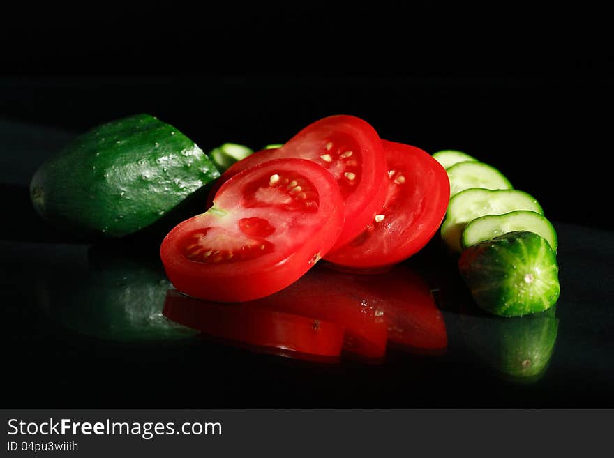 Sliced tomatoes and cucumber on black background. Sliced tomatoes and cucumber on black background