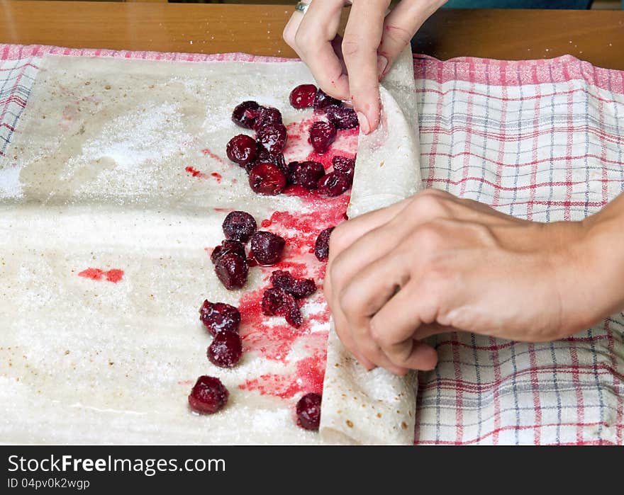 Female hands making small pies with cherry