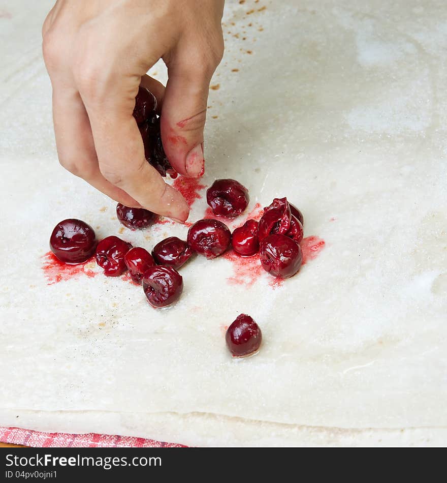 Female hands making small pies with cherry