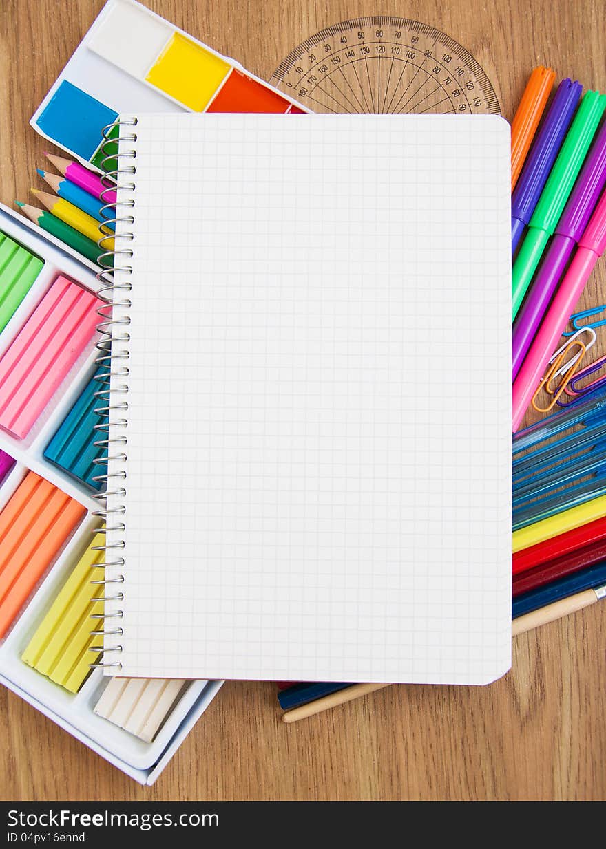 Blank  paper on a school desk with various paints,  pencils and plasticine. Blank  paper on a school desk with various paints,  pencils and plasticine