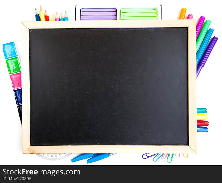 Small elementary blackboard with various paints, crayons and pencils on a white background. Small elementary blackboard with various paints, crayons and pencils on a white background