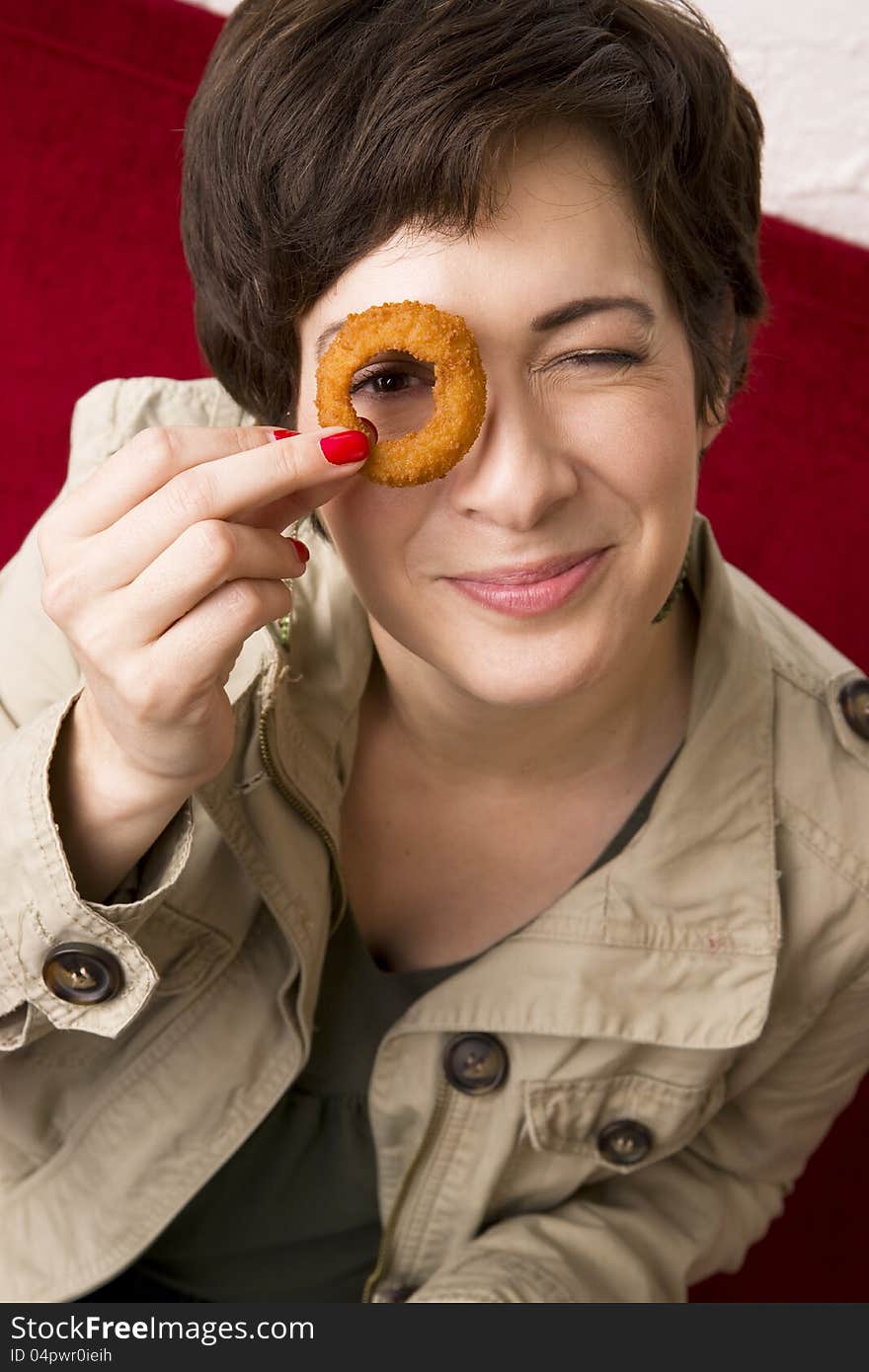 Fun Woman Holds Onion Ring to Eye Smiling