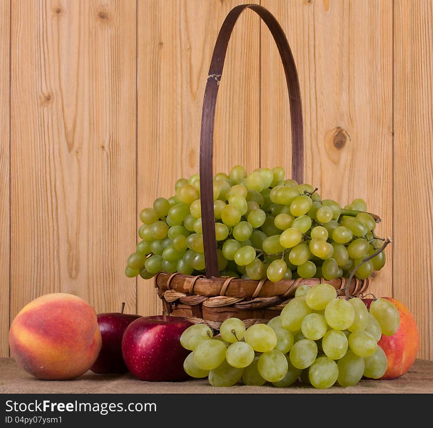 Ripe grapes, peach, apple in the basket. Ripe grapes, peach, apple in the basket