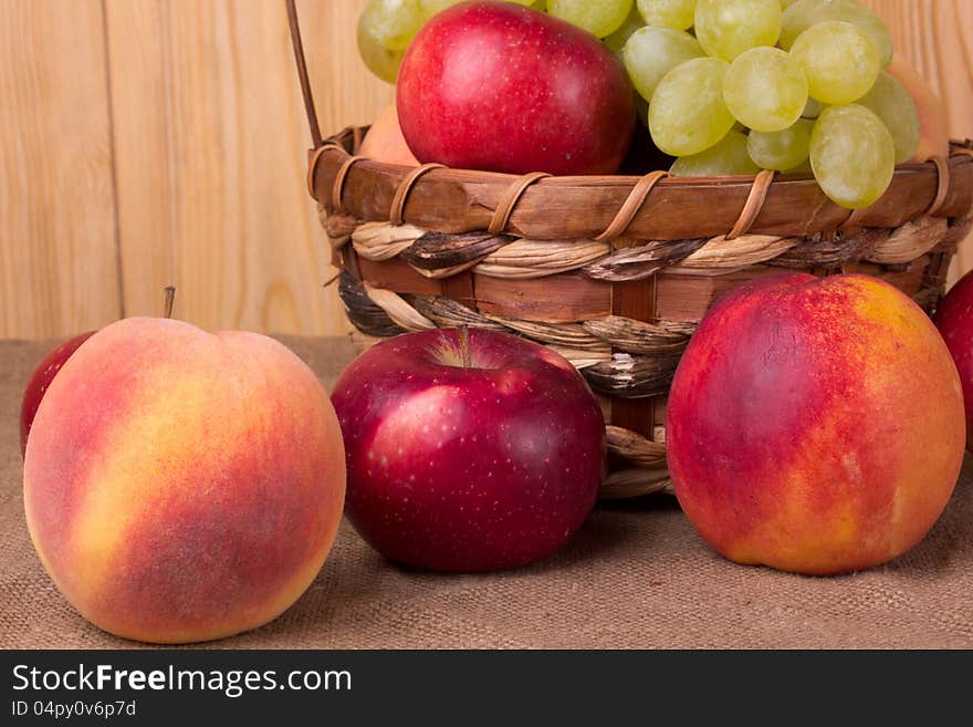 Ripe grapes, peach, apple in the basket. Ripe grapes, peach, apple in the basket