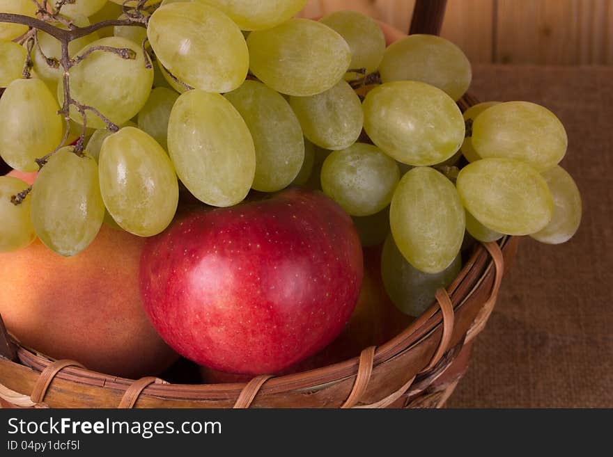 Ripe grapes, peach, apple in the basket. Ripe grapes, peach, apple in the basket