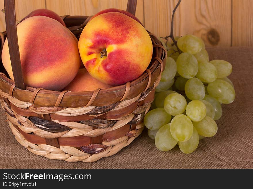 Ripe grapes, peach, apple in the basket. Ripe grapes, peach, apple in the basket