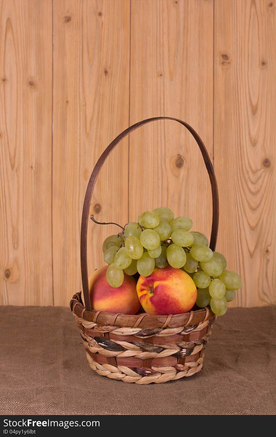 Ripe grapes, peach, apple in the basket. Ripe grapes, peach, apple in the basket