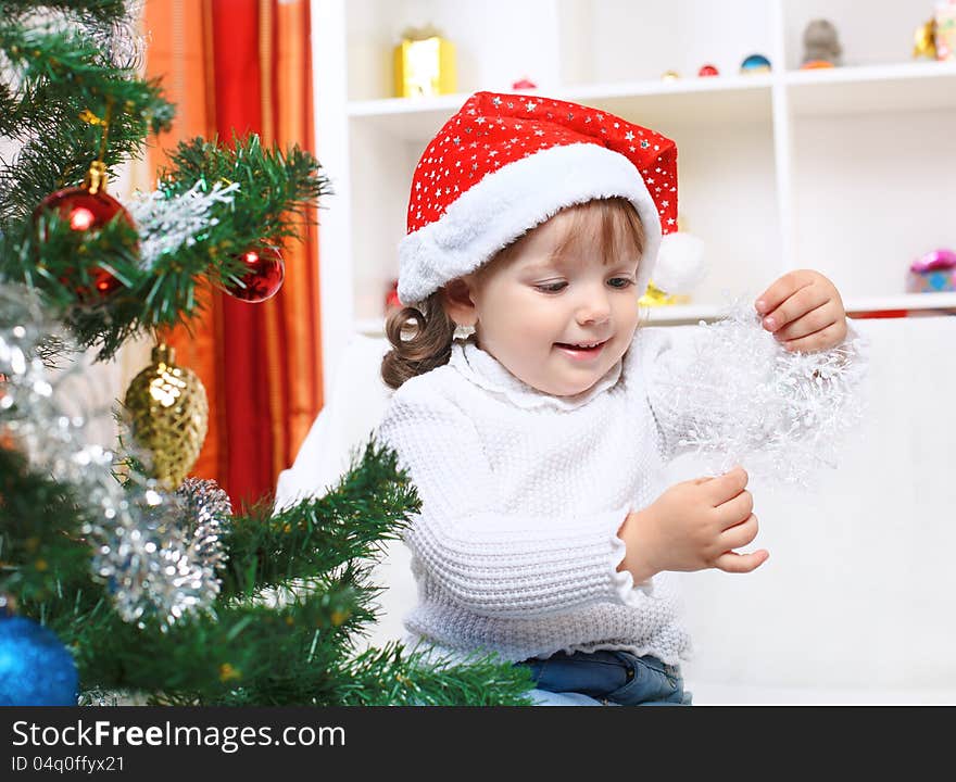 Little girl in Santa's hat looking at the snowflake. Little girl in Santa's hat looking at the snowflake