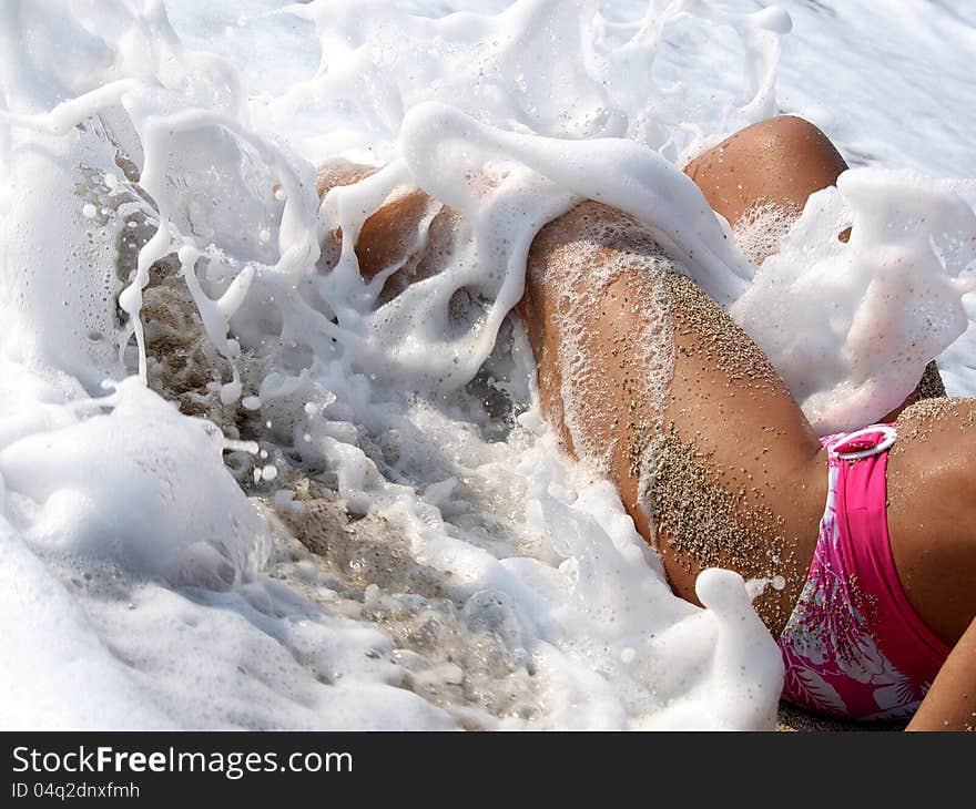 Legs of woman lying in surf