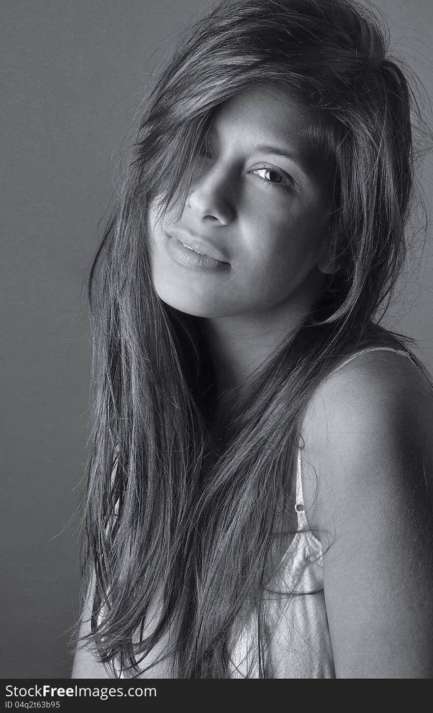 A black and white portrait of a pretty young woman with long, messy hair, smiling slightly at the viewer. A black and white portrait of a pretty young woman with long, messy hair, smiling slightly at the viewer