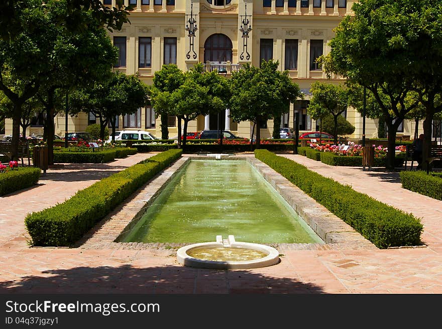 Town hall of Malaga, Spain, as seen from an adjacent park across a water basin in summer. Town hall of Malaga, Spain, as seen from an adjacent park across a water basin in summer.