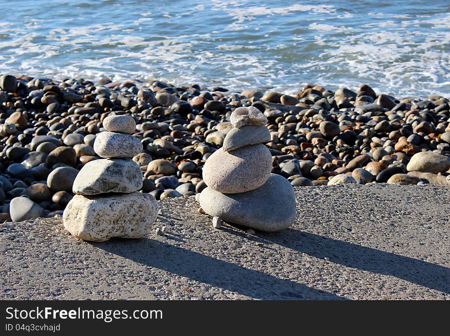 Rocky beach with waves washing over the shore and many pilings of zen stones facing the early morning sunshine. Rocky beach with waves washing over the shore and many pilings of zen stones facing the early morning sunshine.