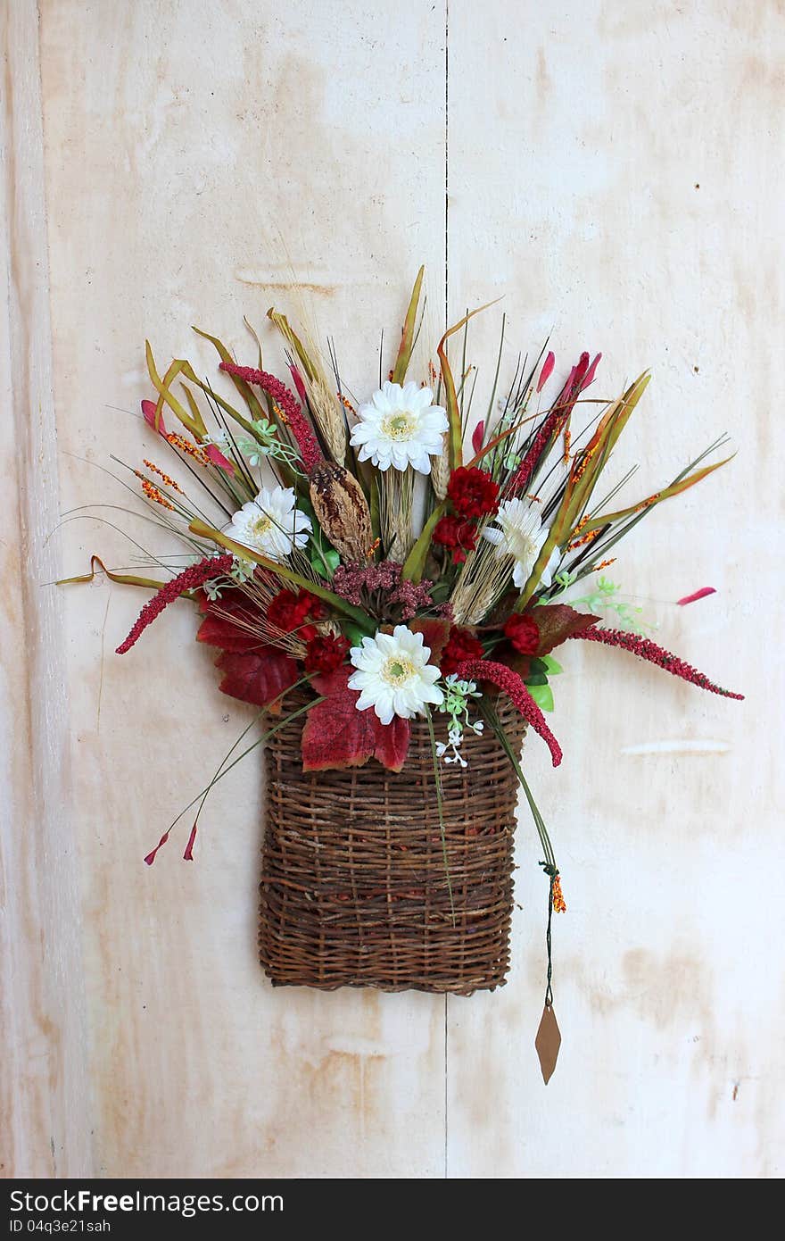 Colorful fall arrangement with flowers and foliage placed together in a woven twig basket. Colorful fall arrangement with flowers and foliage placed together in a woven twig basket.