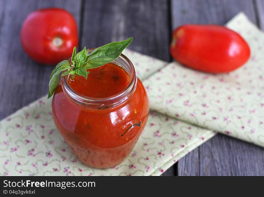 Tomato passata in a jar and two tomatoes