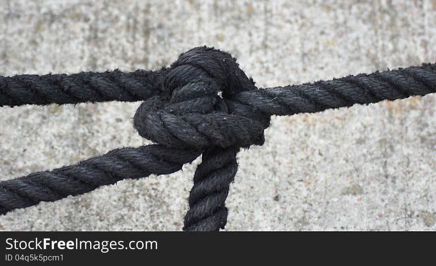 Black rope on gray background - knot. Black rope on gray background - knot