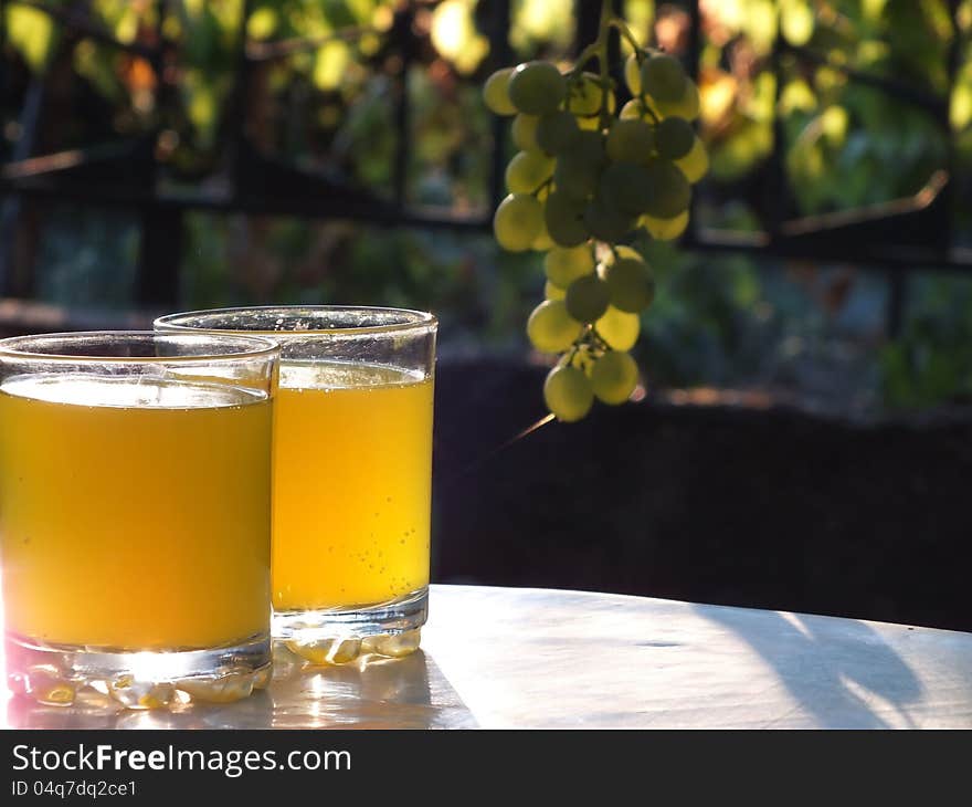 Two glasses of fresh juice on a table in the garden vineyards,photography. Two glasses of fresh juice on a table in the garden vineyards,photography