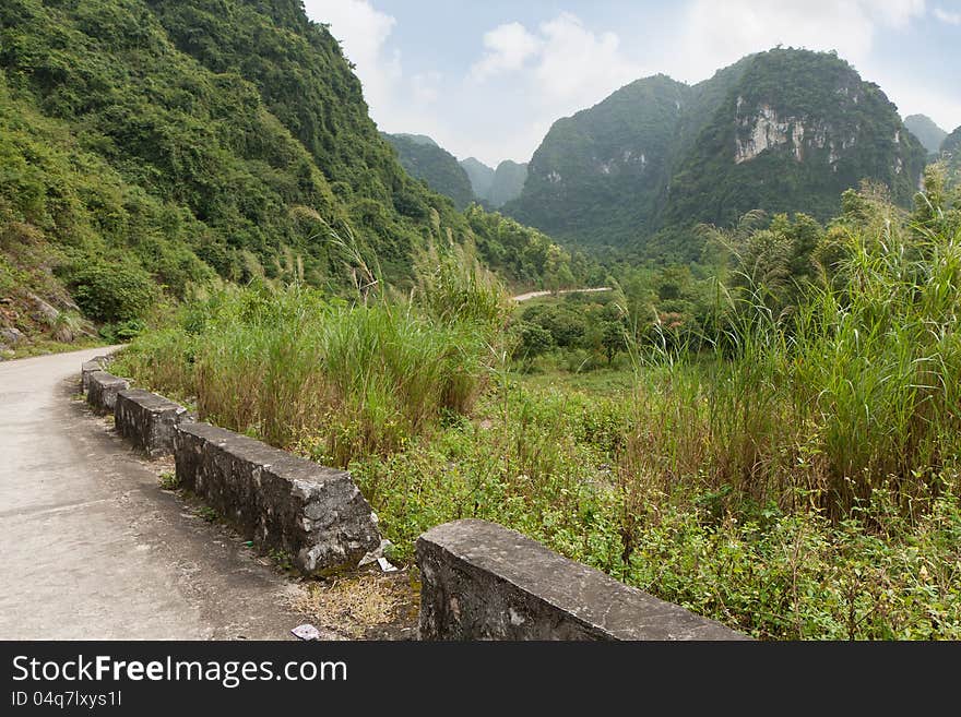 Empty road between green and lush hills and valley at the Cat Ba Island in Vietnam. Empty road between green and lush hills and valley at the Cat Ba Island in Vietnam.