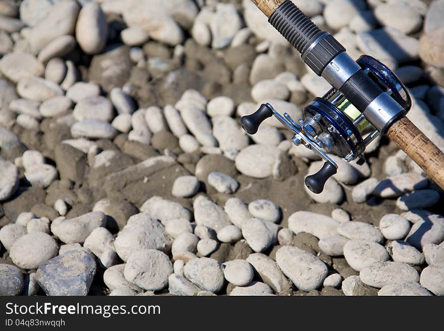 A river fishing rod with level wind reel on gravel