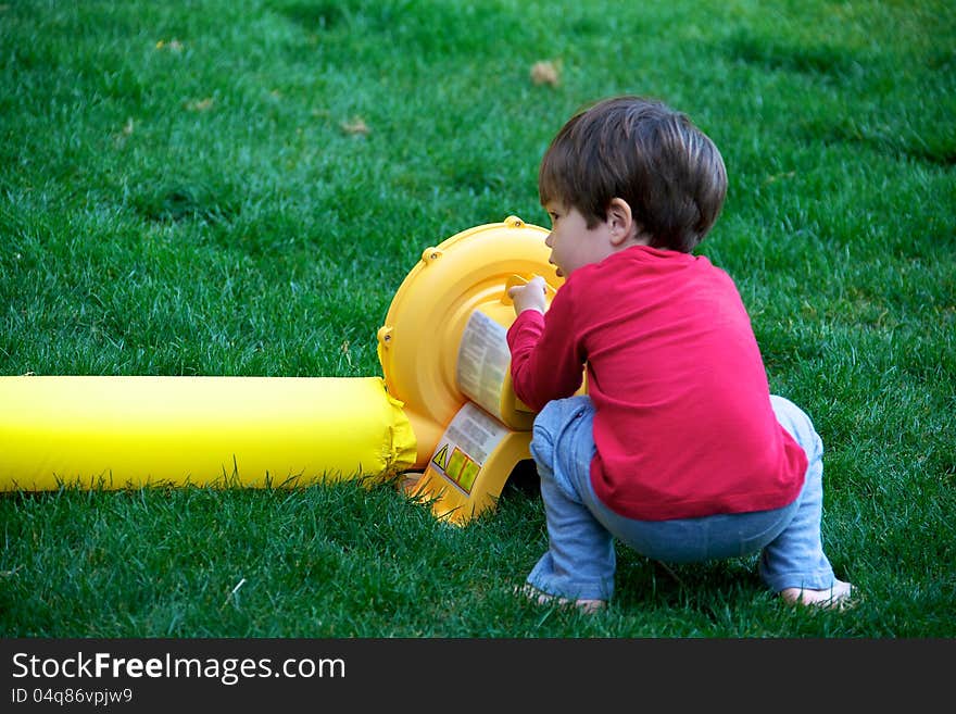 A young boy figuring out how to turn the power on an air blower. A young boy figuring out how to turn the power on an air blower