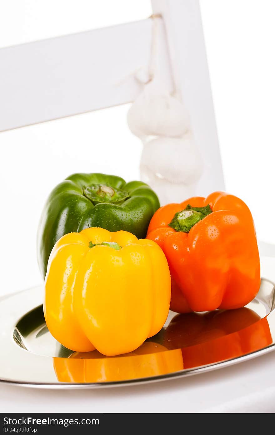 Yellow, orange and green peppers in a silver plate with garlic. Yellow, orange and green peppers in a silver plate with garlic.