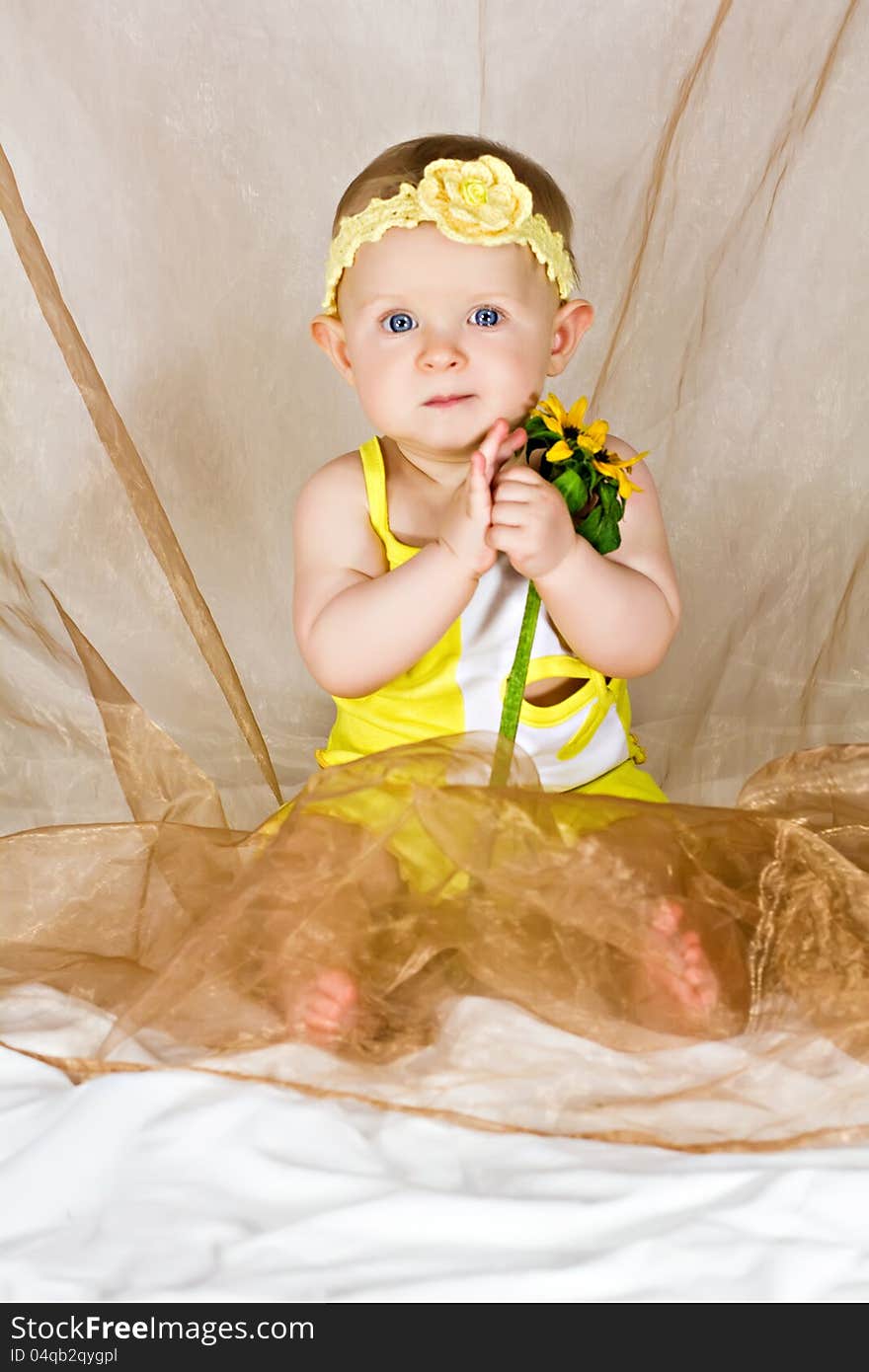 Pretty baby girl taking in her's arms the yellow flower. Pretty baby girl taking in her's arms the yellow flower