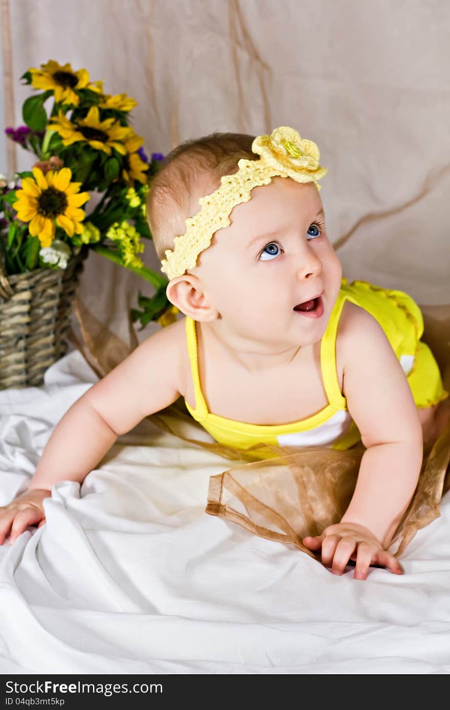 Beautiful baby girl with yellow flowers smiling and looking up. Beautiful baby girl with yellow flowers smiling and looking up