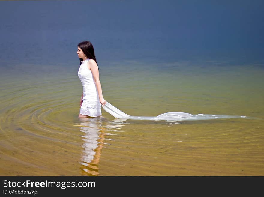 Woman in white dress in the water of the lake