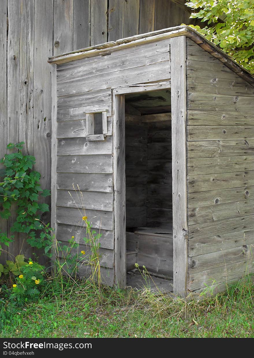 Old gray wooden outhouse.