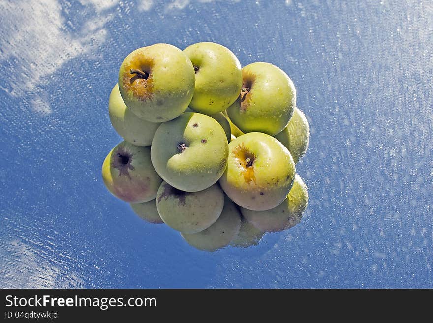 Yellow apples stocked in pyramid on wet, reflective glass. Yellow apples stocked in pyramid on wet, reflective glass.