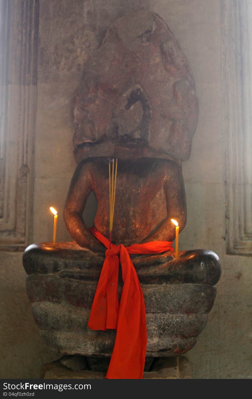 Candles burning and cloth at an old Hindu statue at Angkor Wat temple in Cambodia.