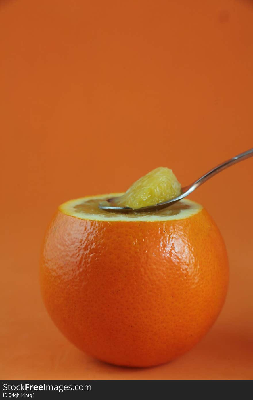 The orange with a spoon on yellow background