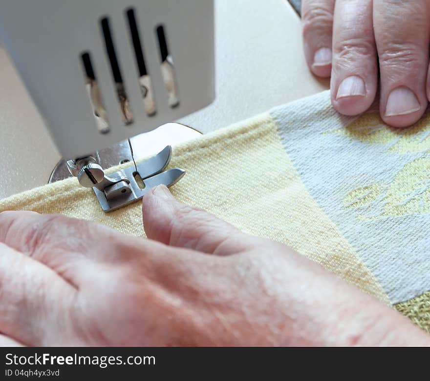 An elderly woman sew on a typewriter