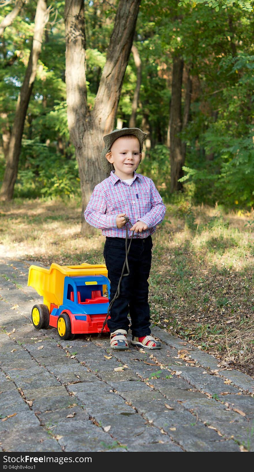 Boy pulling a toy truck on a paved lane