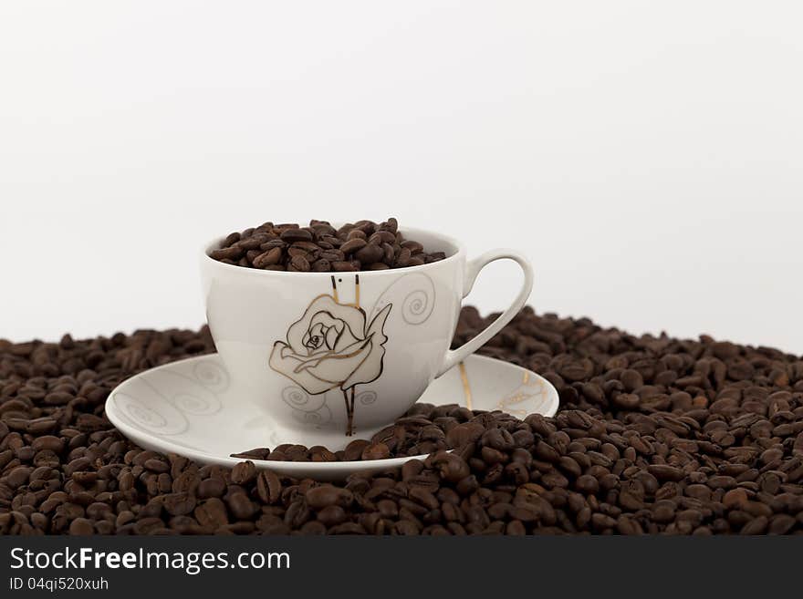 Coffee beans in cup on white background