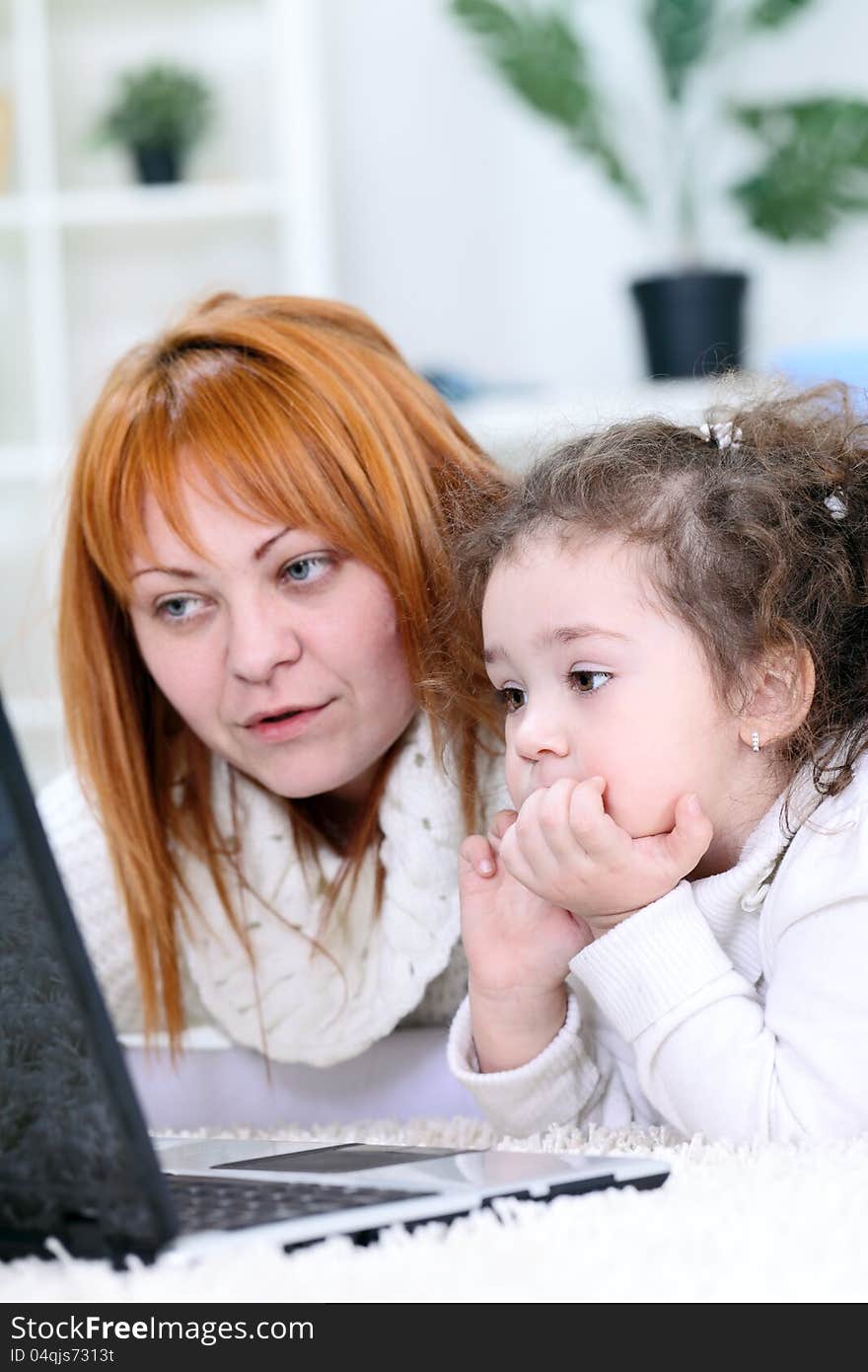 Young women with daughter using laptop computer at home. Young women with daughter using laptop computer at home