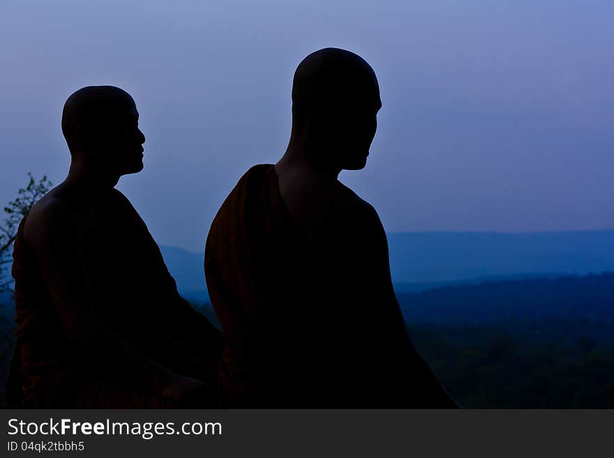 Silhouette of monk meditating at the top of the mountain