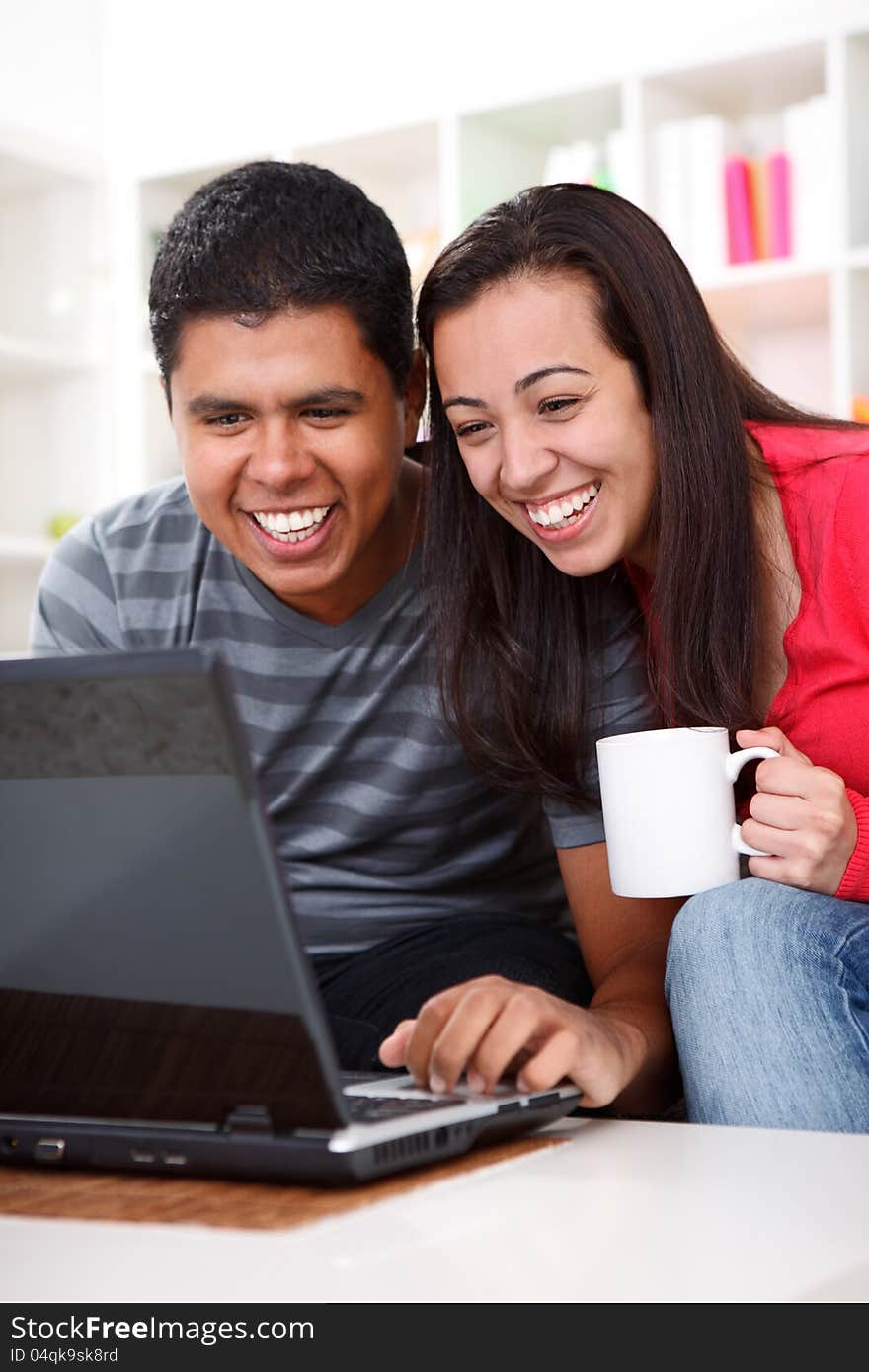 Laughing young couple looking at laptop in home. Laughing young couple looking at laptop in home