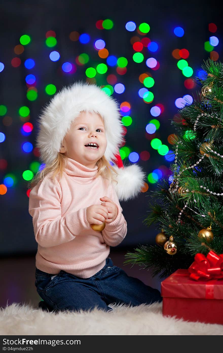 Baby decorating Christmas tree on bright backdrop