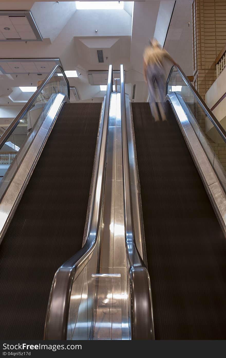 Dual escalators with steps blurred by motion inside a shopping mall. Dual escalators with steps blurred by motion inside a shopping mall.