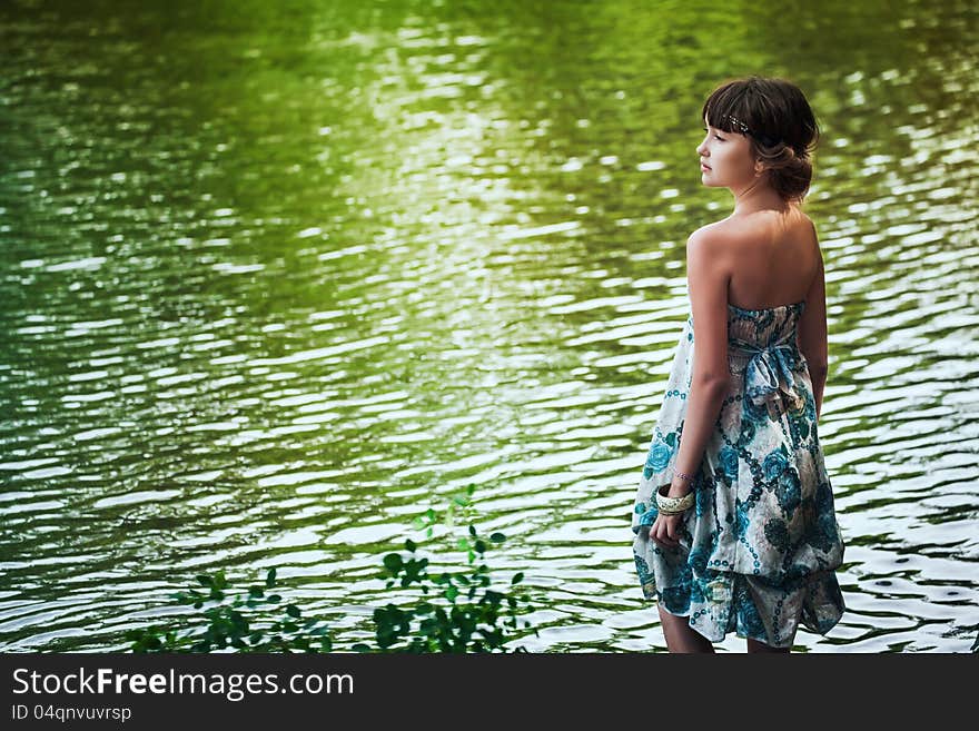 Girl in blue dress stayingby a lake. Girl in blue dress stayingby a lake